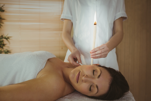 Young woman getting an ear candling treatment in therapy room